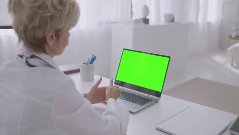 Eine-Ärztin-Hört-Dem-Patienten-Während-Der-Online-Konsultation-Zu-Und-Schaut-Auf-Den-Grünen-Bildschirm-Des-Laptops,-Um-Festzustellen,-Ob-Die-Chroma-Key-Technologie-Aus-Der-Ferne-Funktioniert